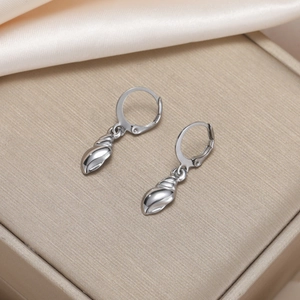Close-up of silver conch shell pendant lever-back earrings on elegant beige jewelry box