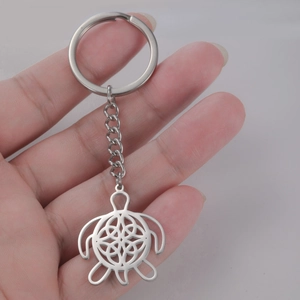 Detail showing a silver turtle keychain with Celtic knot pattern held in hand