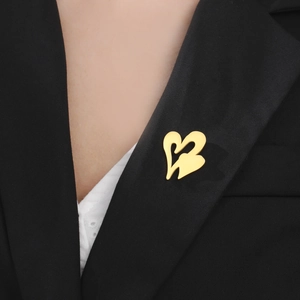 Detailed view of a gold double heart brooch pinned on a black suit lapel for elegance