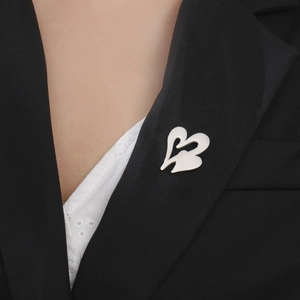 Detail of silver heart-shaped stainless steel brooch on a black suit lapel