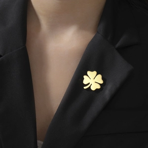 Polished gold four-leaf clover brooch pinned on dark suit lapel for business fashion