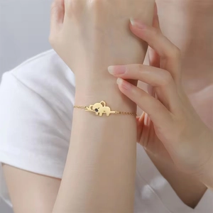 Detail van een gouden koala-armband aan de vrouwelijke pols met minimalistische schakels