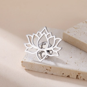 Detailed view of silver stainless steel lotus flower brooch on minimalist stone stand