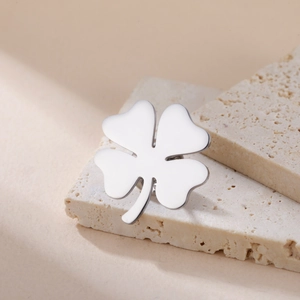 Detail of silver stainless steel four-leaf clover brooch on aesthetic stone display