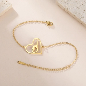 Detailed macro view of gold stainless steel heart charm with gymnast silhouette on bracelet