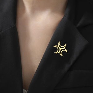 Detail of a minimalist gold cross star brooch pinned on a black blazer lapel