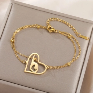 Detail of gold double-layer chain bracelet featuring a heart gymnast silhouette pendant