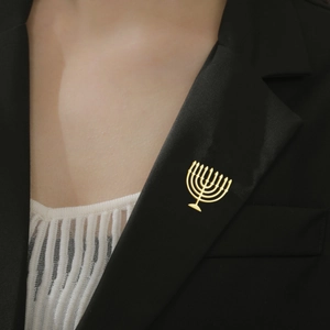 Close-up of a golden Menorah brooch pinned on a black suit lapel for a formal look