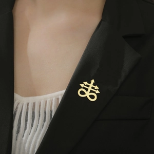Detail of a golden Leviathan cross brooch pinned on a black suit lapel for styling