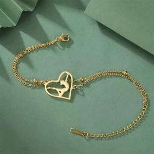 Detail of gold double-layer chain bracelet featuring a gymnastic heart pendant charm