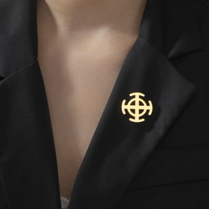Detail of a golden cross brooch on a black suit lapel, polished stainless steel finish