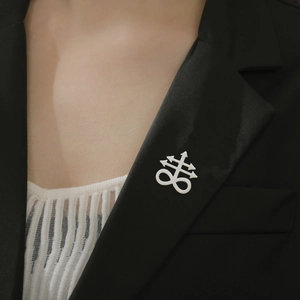 Macro detail of a white Leviathan Cross pin on a black blazer for a gothic aesthetic