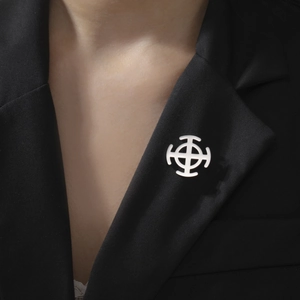 Detailed view of a silver minimalist cross brooch pinned on a black suit lapel