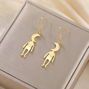 Detailed macro view of golden surrealist moon-head earrings on a silk background
