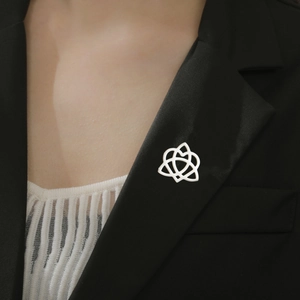 Silver Celtic knot brooch worn on a black suit lapel, featuring polished geometric design