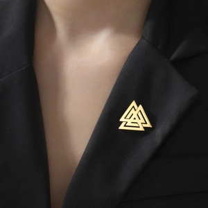 Close-up of a golden Valknut triangle brooch pinned on a black textured blazer lapel