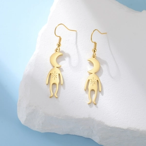 Macro view of gold celestial planet figure earrings on a textured white stone base