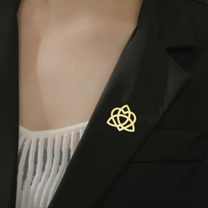 Close-up of golden interlocking geometric brooch pinned on a black suit lapel