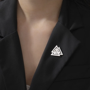 Detailed view of silver interlocking triangles brooch on a black suit lapel