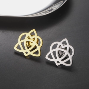 Macro view of gold and silver Celtic knot brooches with butterfly pins on black background