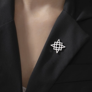 Close-up of a silver geometric cross brooch on a black blazer lapel for modern style
