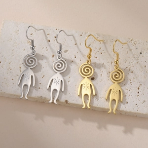 Detail of creative planet-man earrings in gold and silver finish on a stone display