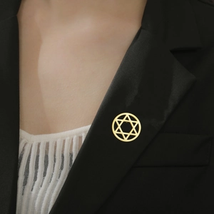 Detail of a gold hexagram brooch pinned on a black suit lapel for a luxury business look