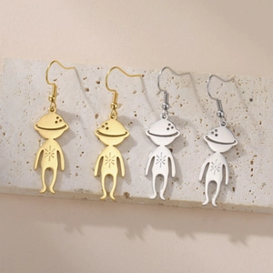 Detail of cute alien planet pendants in gold and silver steel on a textured stone plate
