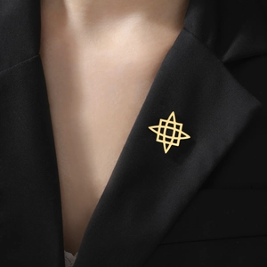 Detail of a minimalist gold geometric star brooch pinned on a black suit lapel