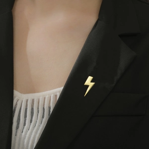 Close-up of a lightning bolt lapel pin in polished gold plating on a black suit lapel