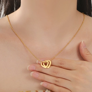 Collier minimaliste avec double pendentif cœurs entrelacés en finition dorée