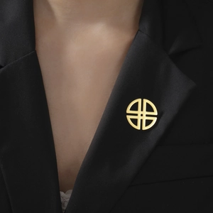 Detail of a minimalist gold cross brooch pinned on a black suit lapel for a modern look