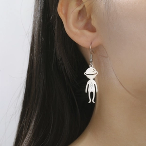 Close-up of minimalist stainless steel cartoon alien drop earring worn by a model