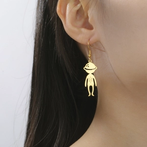 Detailed close-up of a gold-plated alien pendant earring worn by a model