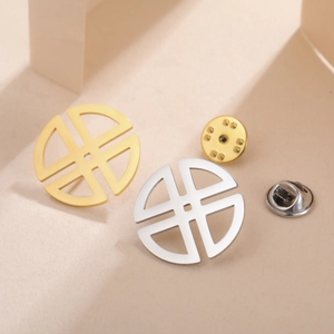 Detailed macro view of minimalist cross cut-out round brooches in gold and silver finish