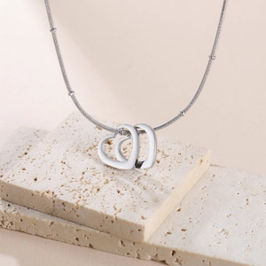 Détail de pendentifs cœurs entrelacés sur un collier chaîne serpent perlée en argent