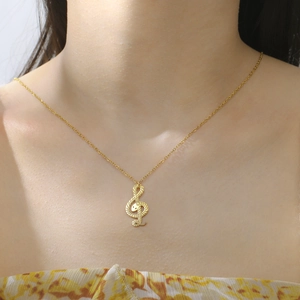 Gouden muzieksleutel ketting met slangentextuur gedragen door een model om de nek