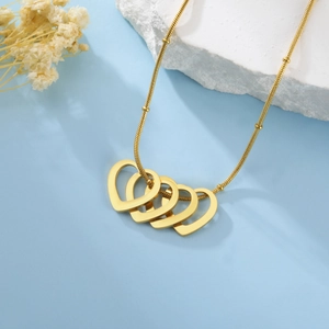Détail macro du collier serpent en acier inoxydable doré avec des pendentifs coeurs entrelacés