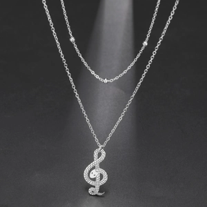 Detail van zilveren dubbele ketting met kralenketting en slangentextuur muziek hanger