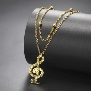 Detail van gouden slang-vioolsleutel hanger met schubtextuur op roestvrijstalen kralenketting