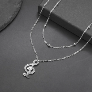 Macro-opname van zilveren roestvrijstalen slangenketting met een vioolsleutel hanger