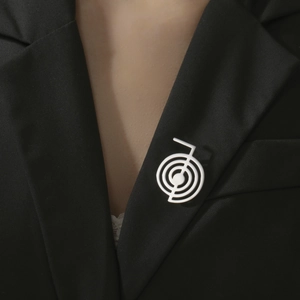 Detailed close-up of a silver spiral metal brooch pinned on a black suit lapel