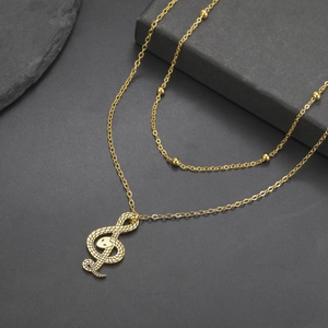 Detail van gouden dubbellaagse ketting met een getextureerde vioolsleutel hanger met slang