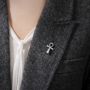 Close-up of silver Ankh cross brooch on grey herringbone suit lapel for fashion style