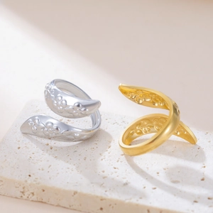 Dettaglio ravvicinato di anelli in oro e argento con goffratura floreale su base di pietra