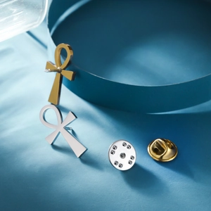 Detailed view of gold and silver Ankh cross pins with butterfly clasp backings
