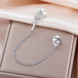 Polished 304 stainless steel tennis racket brooch with chain on silk background