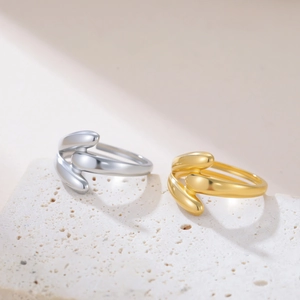 Dettaglio di anelli a goccia in oro e argento su base in pietra con ombre eleganti