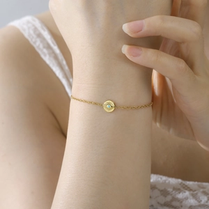 Golden stainless steel bracelet with blue evil eye pendant on a woman's wrist