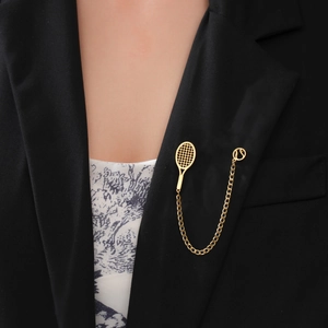 Detailed view of a gold-tone tennis racket brooch pinned on a black suit lapel